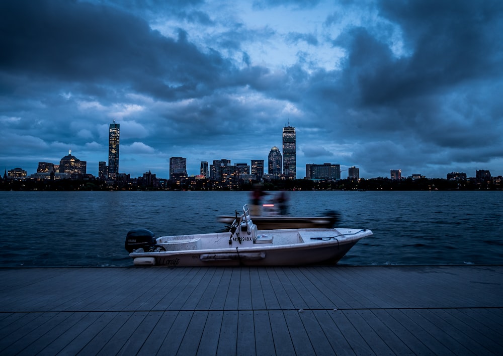 white and black boat on sea dock near city buildings under cloudy sky during daytime
