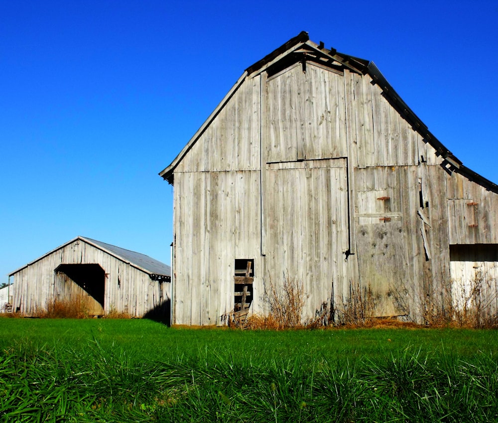 brown wooden barn on green grass field under blue sky during daytime