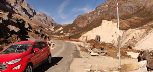 A red compact SUV ready for a weekend getaway in the mountains with luggage on the roof.