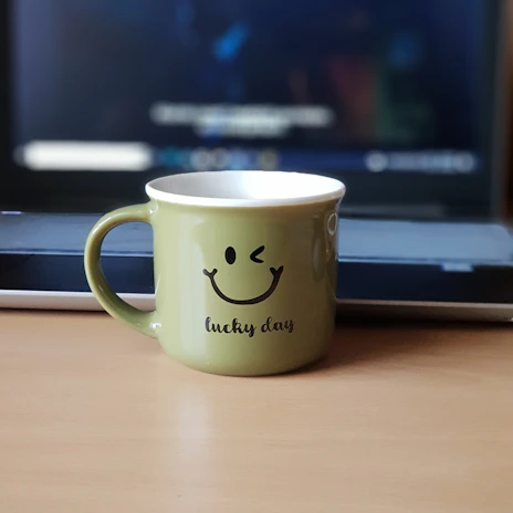 white and black ceramic mug on brown wooden table