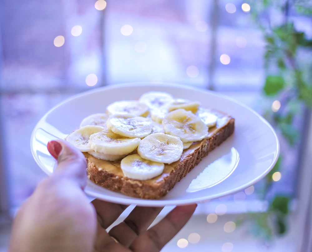 person holding brown bread on white ceramic plate