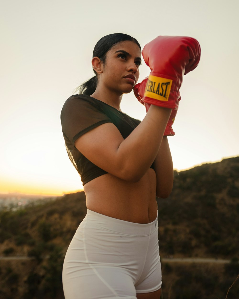 woman in brown tank top and white shorts holding red and white plastic bottle