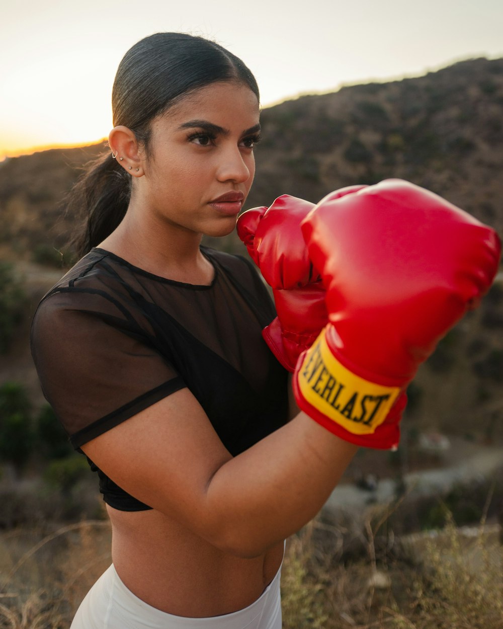 mulher na regata preta que segura luvas de boxe vermelhas