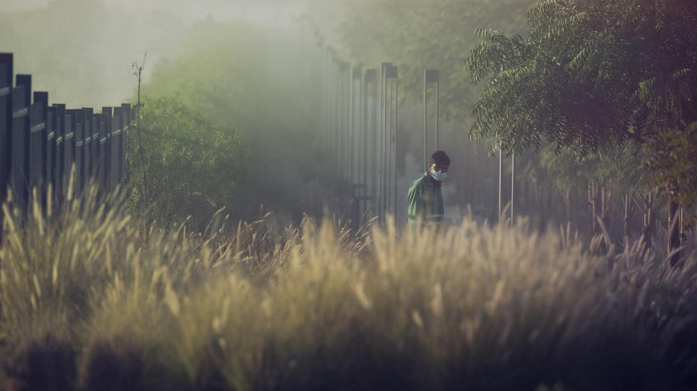 man in green jacket walking on green grass field during daytime