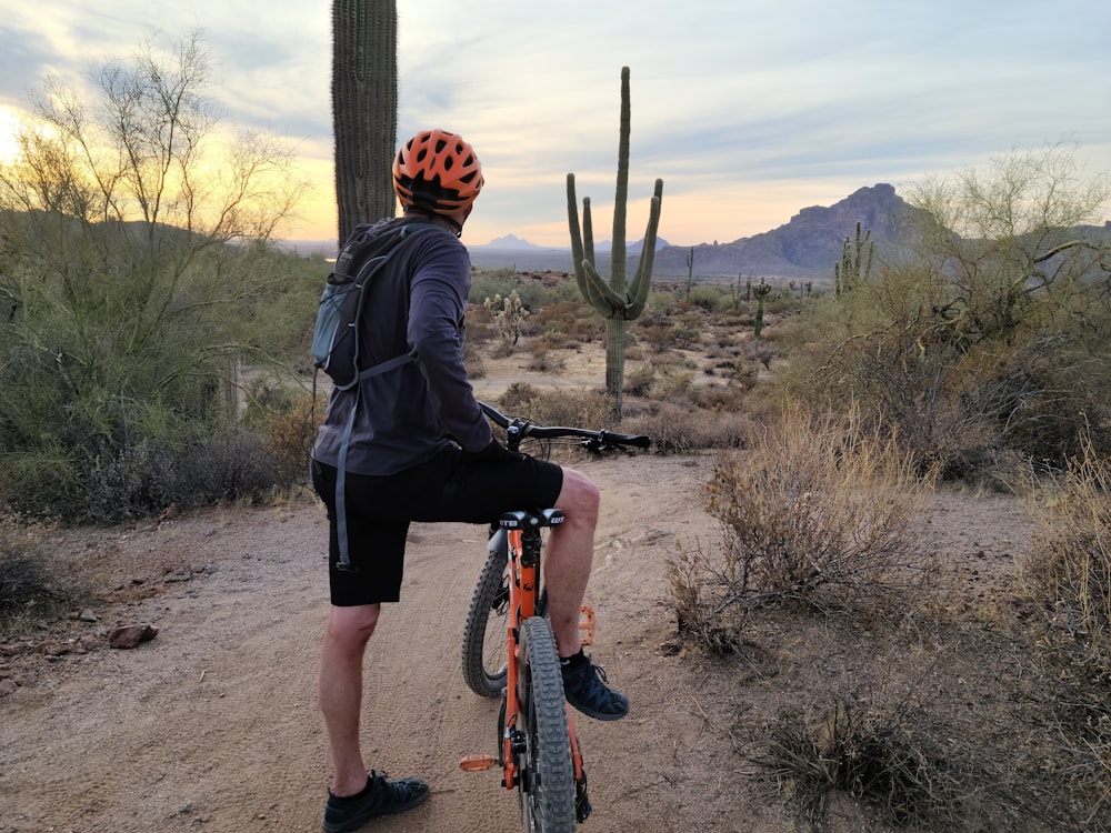 man in black jacket and black pants riding on bicycle during daytime