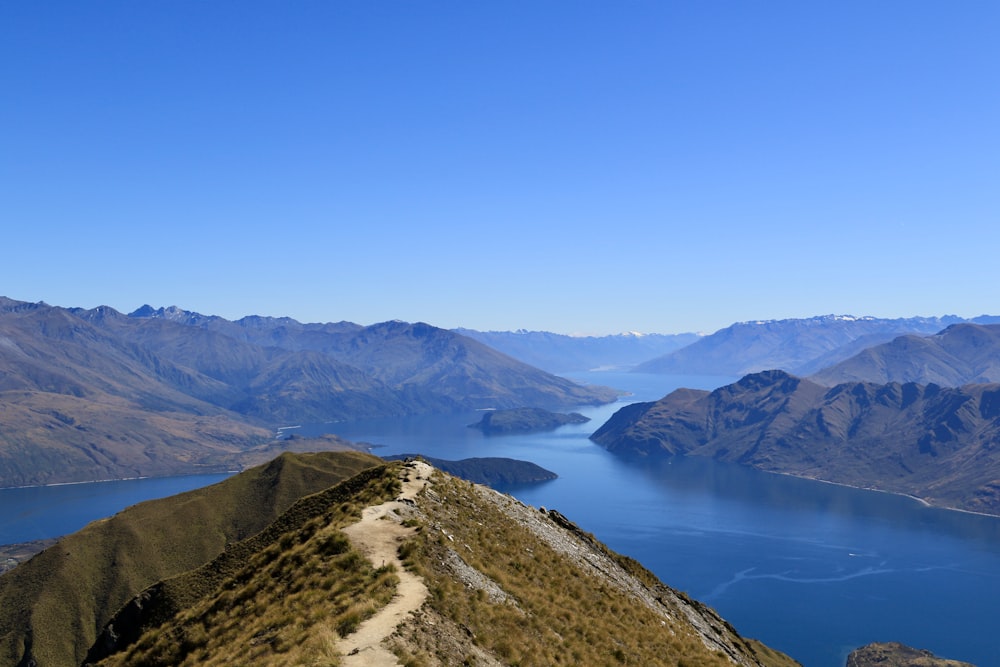 montagna verde e marrone accanto al lago sotto il cielo blu durante il giorno