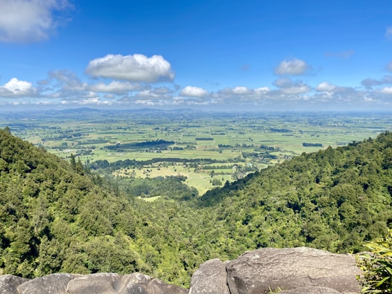 A panoramic view of fertile land in Wayanad with rolling hills and clear blue skies.