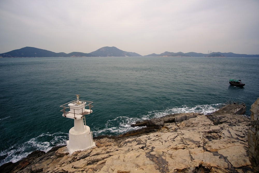 white cross on brown rock near body of water during daytime