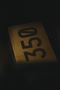A cardboard box with the number 350 printed prominently in large, black, bold characters is situated in dim lighting, creating a mysterious or subdued atmosphere.