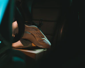 Detail shot of stacked sneaker boxes in a minimalist dark room lit by soft colored lighting.