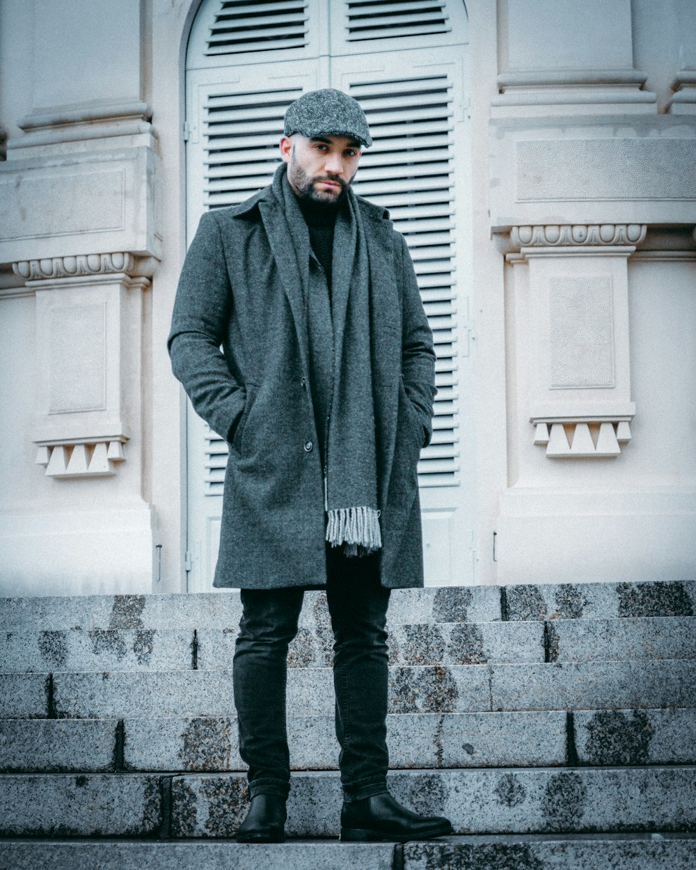 man in gray coat standing on gray concrete floor during daytime