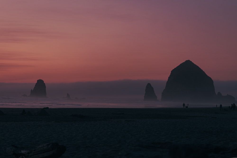 silhouette of rock formation on sea during daytime