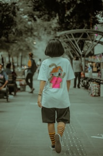 girl in white crew neck t-shirt and black shorts running on gray concrete pavement during