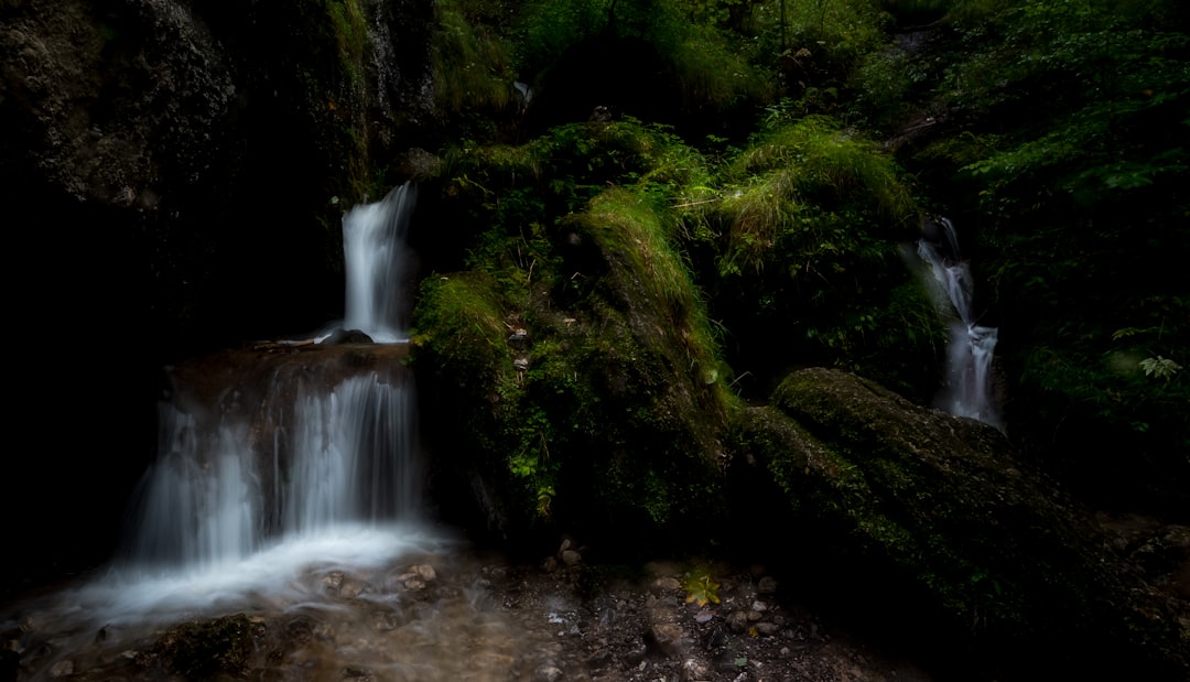 water falls in the middle of green moss covered rocks