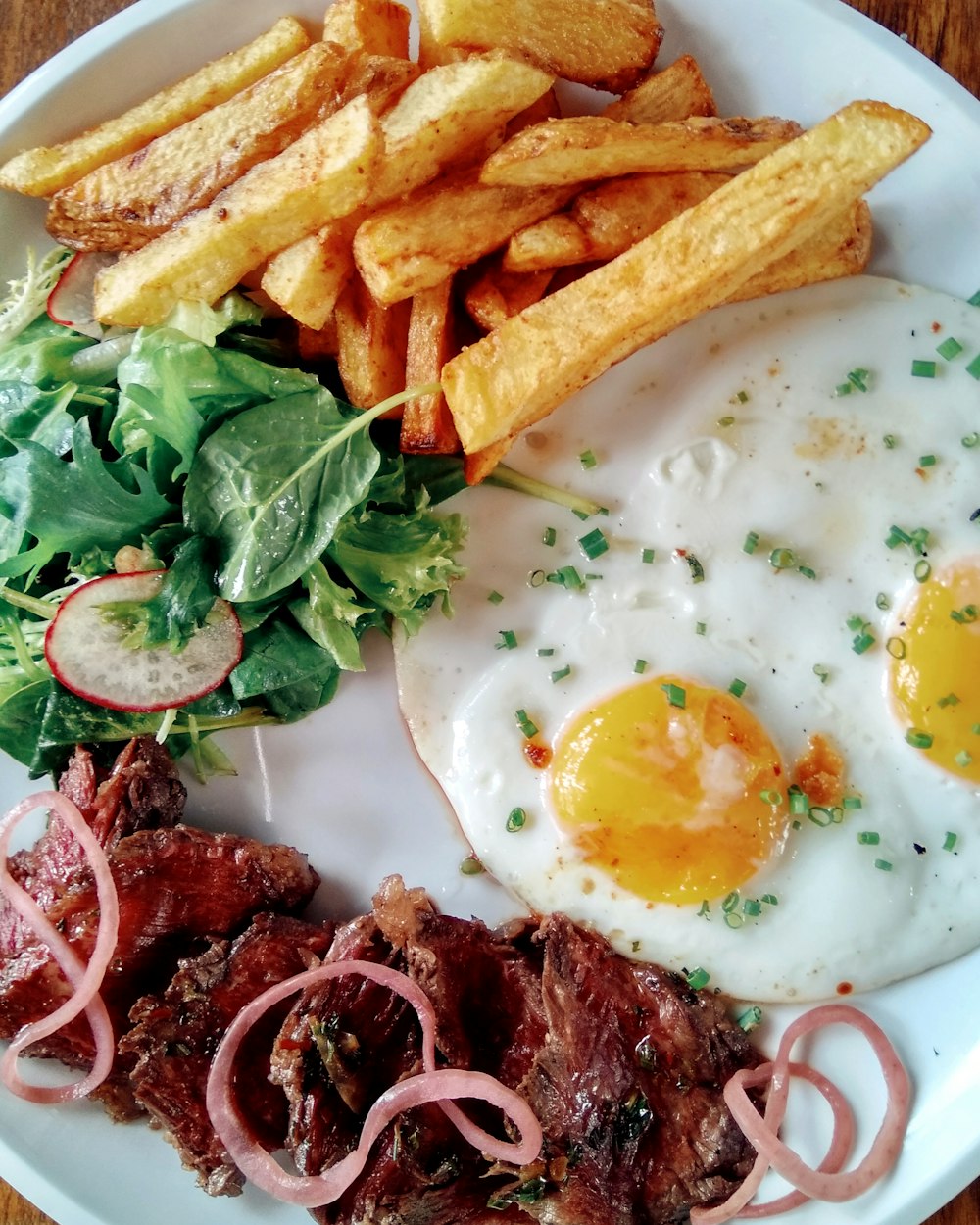 fried fries with sunny side up egg and sliced vegetable