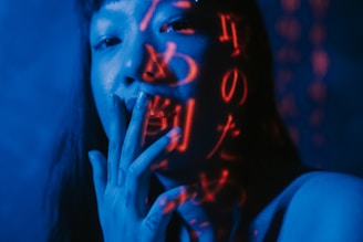 An intense close-up of a hero character from a new anime trailer, illuminated by cyan and magenta highlights.