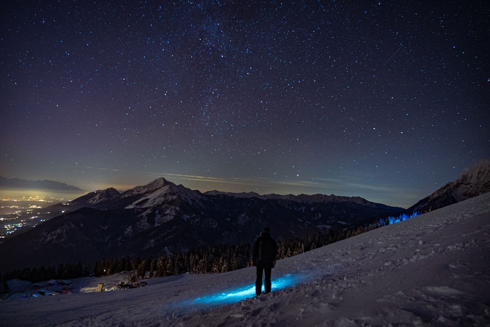 person in black jacket standing on snow covered ground during night time