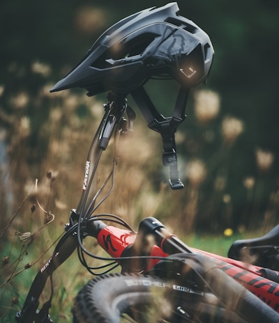 black and red bicycle helmet on brown grass during daytime