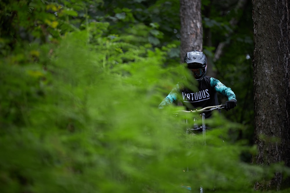 homem na jaqueta verde que monta a bicicleta no campo verde da grama durante o dia