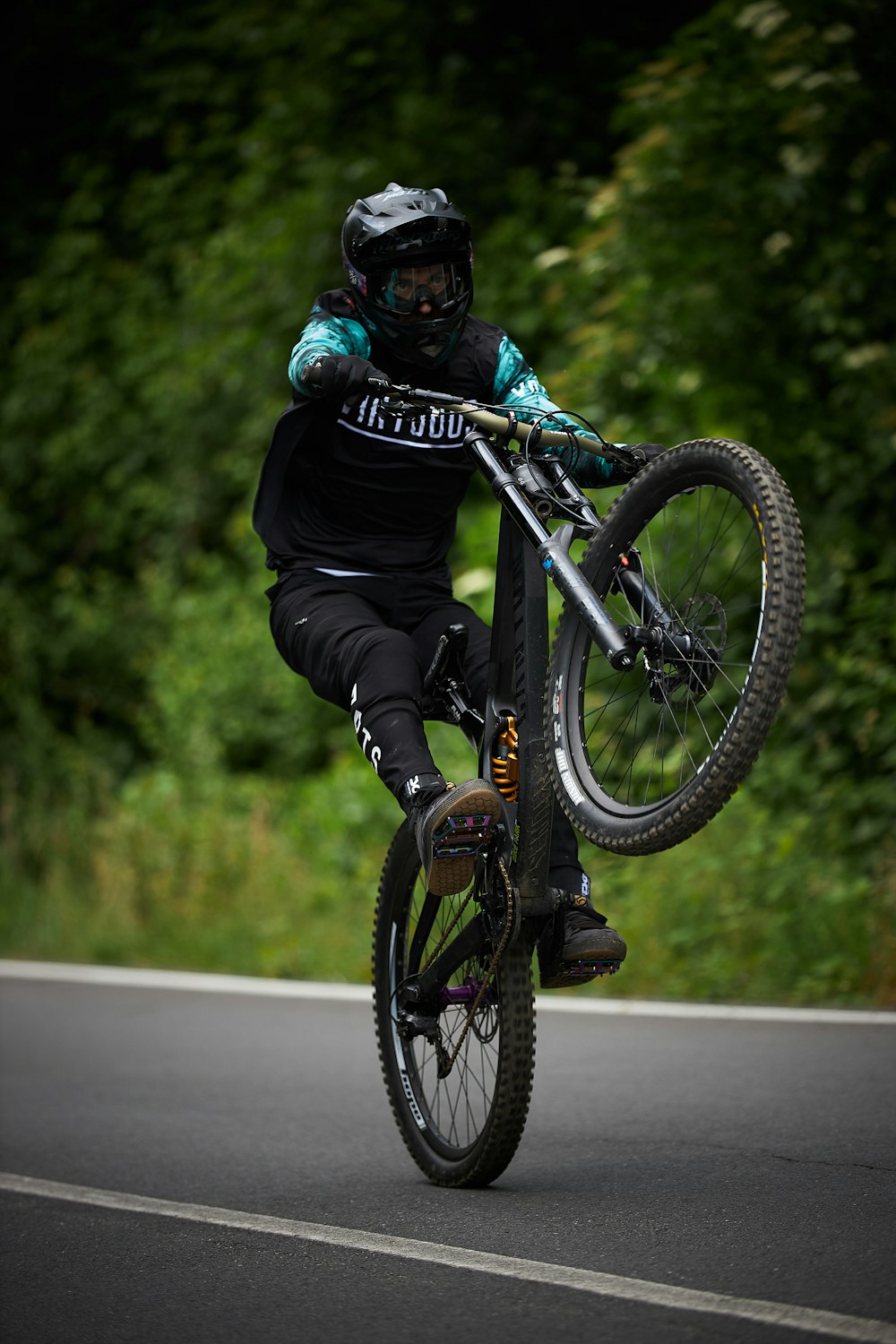 homem no capacete preto que anda na mountain bike preta na estrada durante o dia