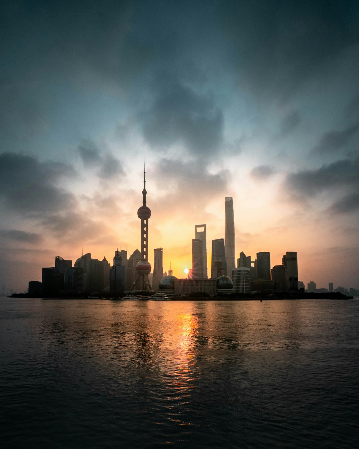 Shanghai skyline at sunrise across the Huangpu River, showing the financial district's towering skyscrapers