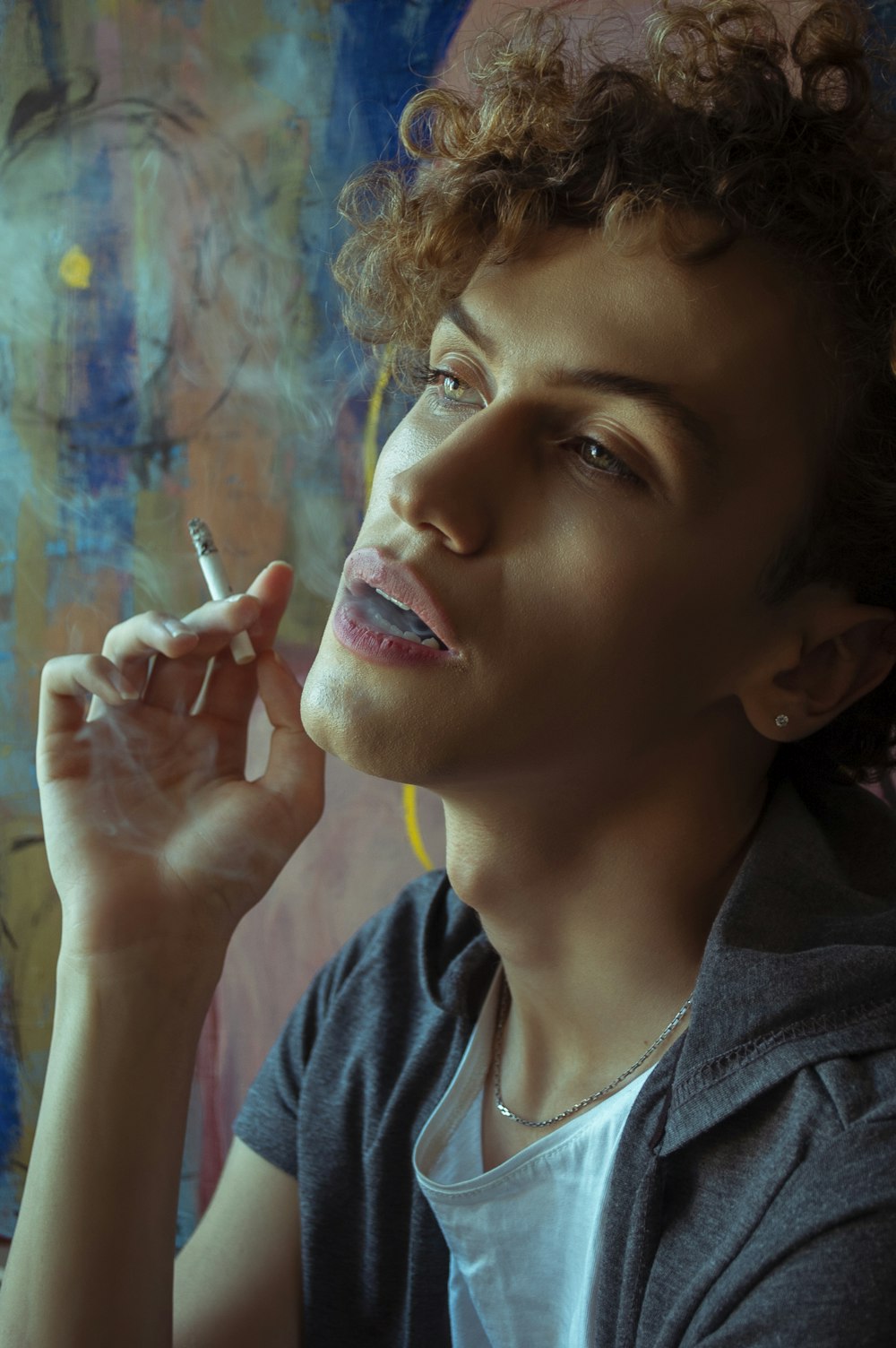 woman in blue crew neck shirt holding cigarette stick