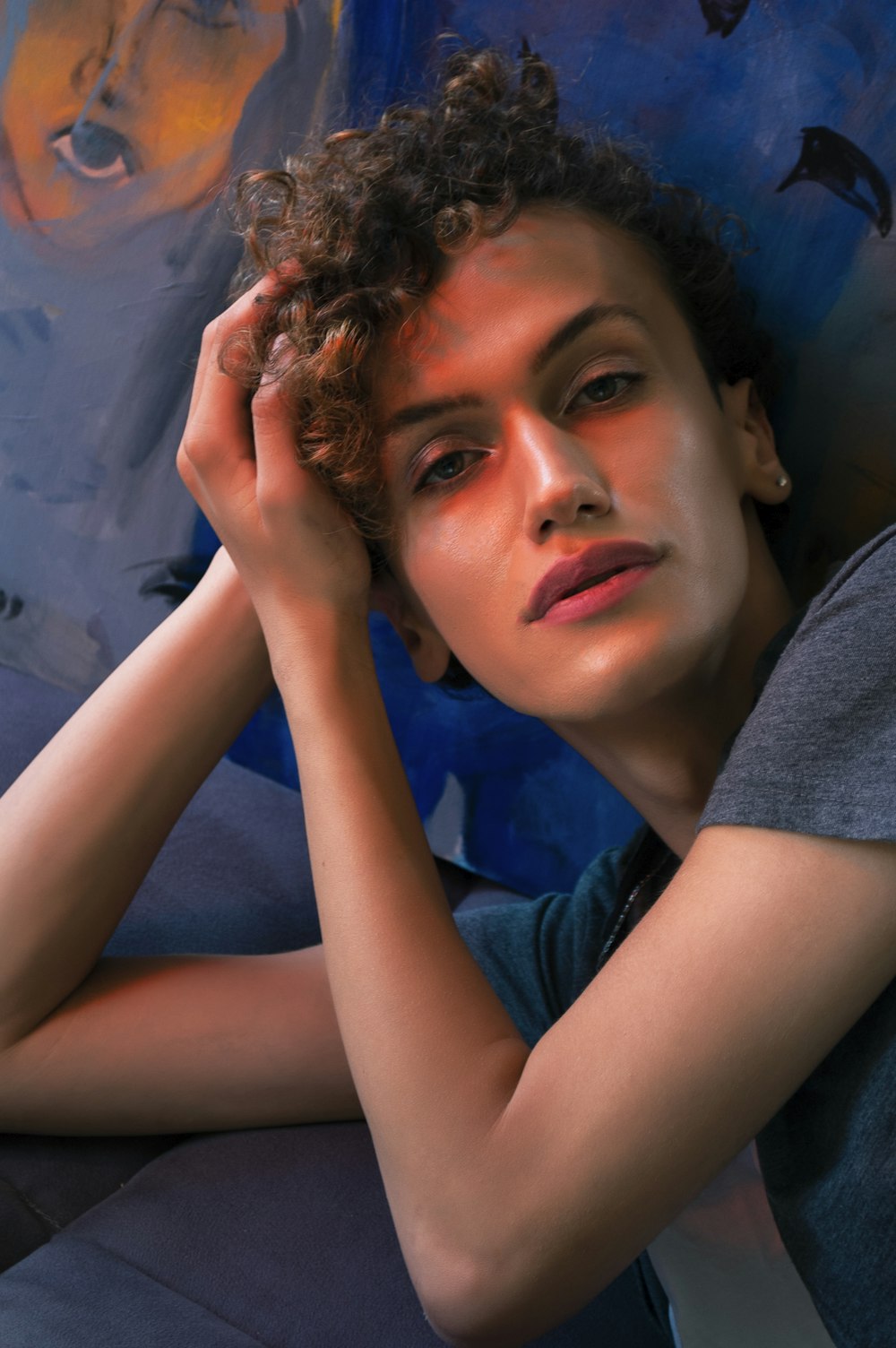 woman in gray shirt lying on blue textile