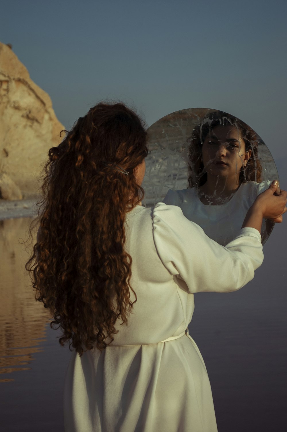 woman in white long sleeve shirt standing near body of water during daytime