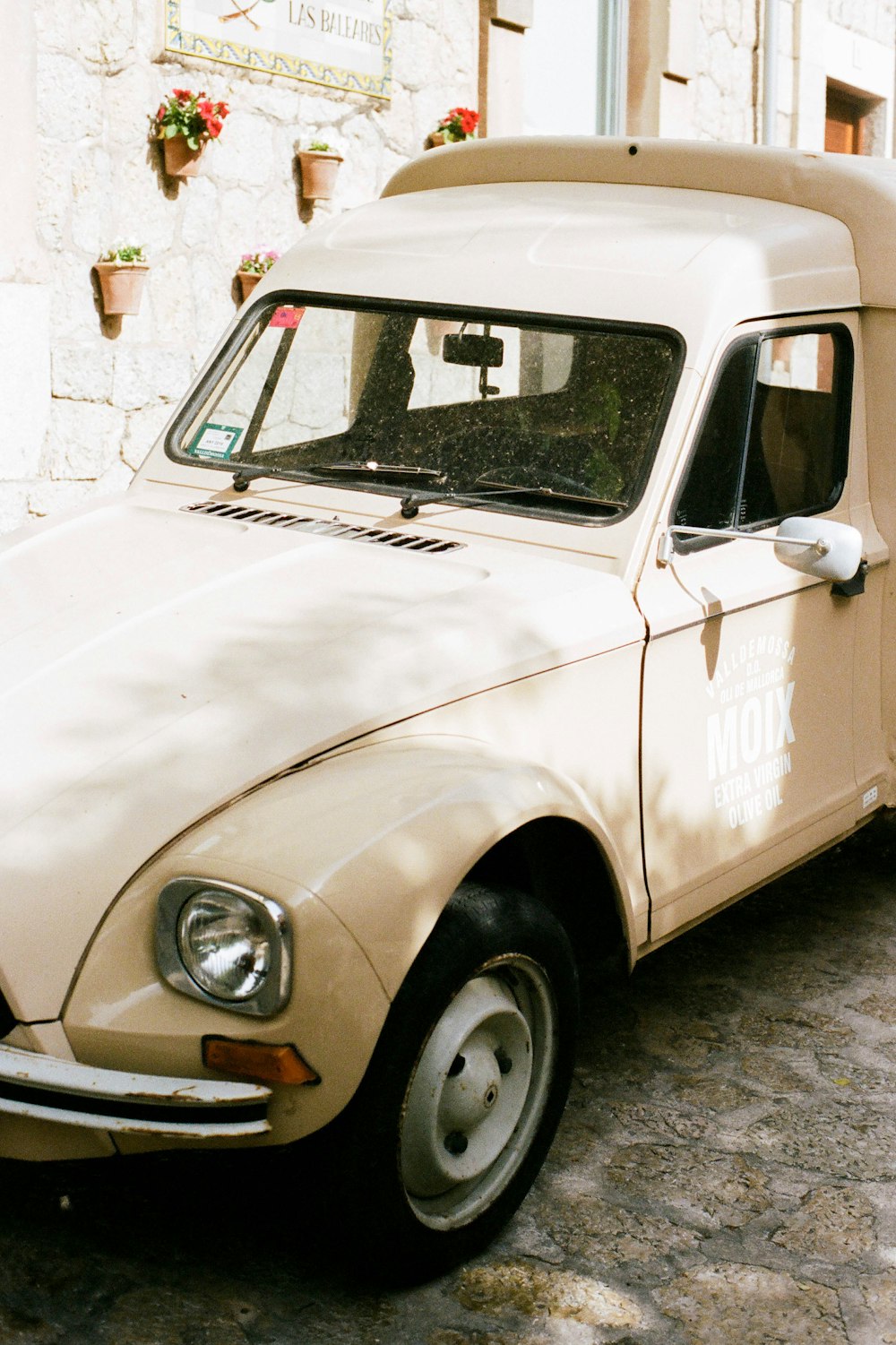 white vintage car parked beside brown brick wall