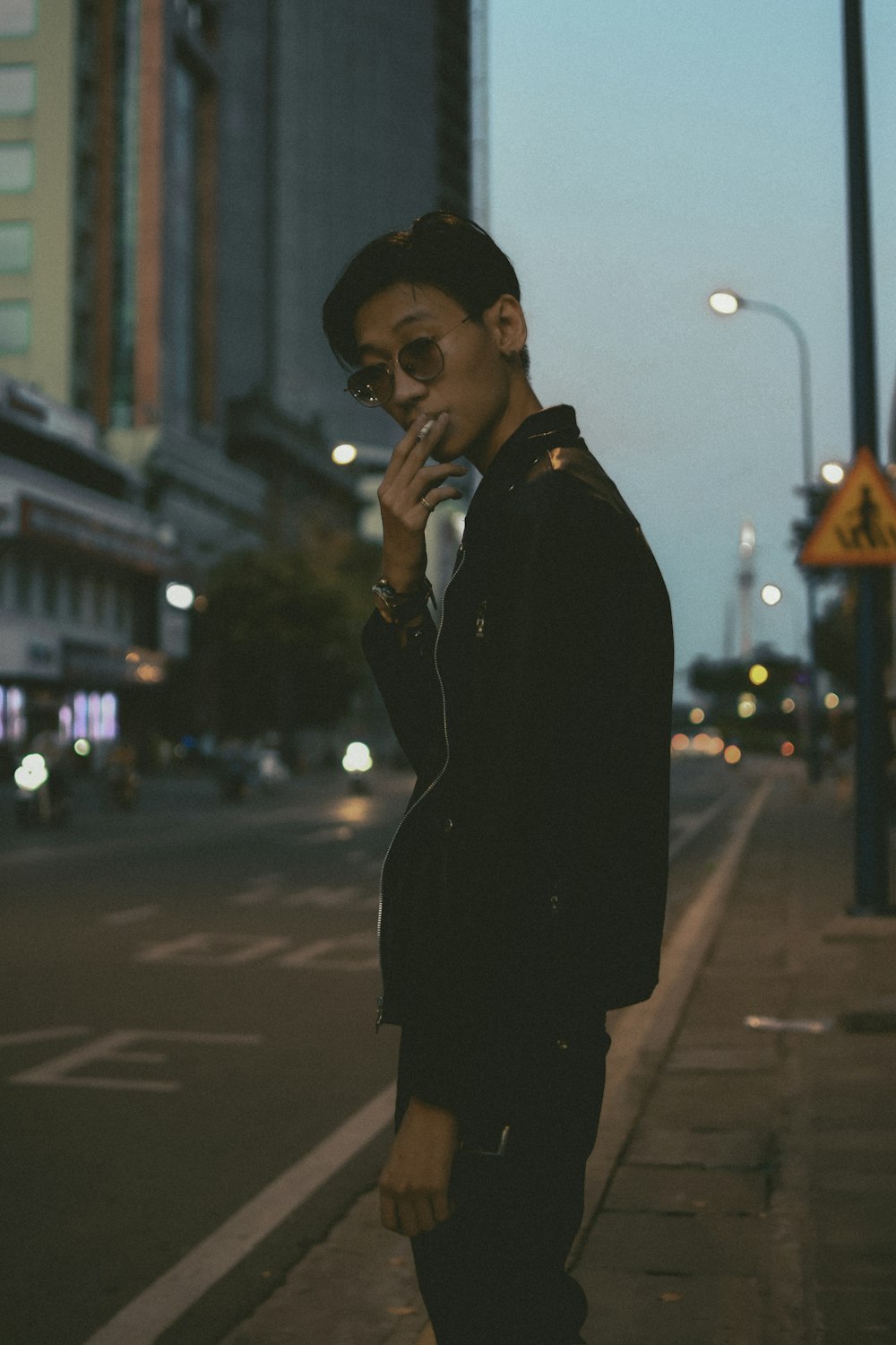 man in black coat standing on sidewalk during night time