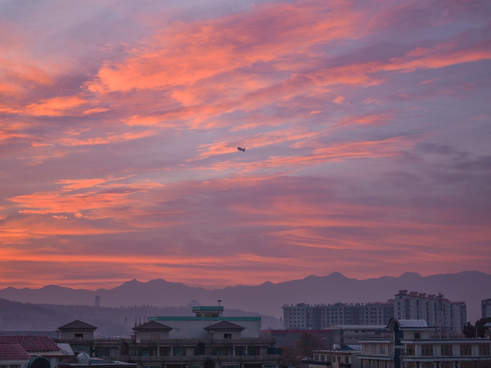 white and brown concrete buildings under orange and gray cloudy sky during sunset