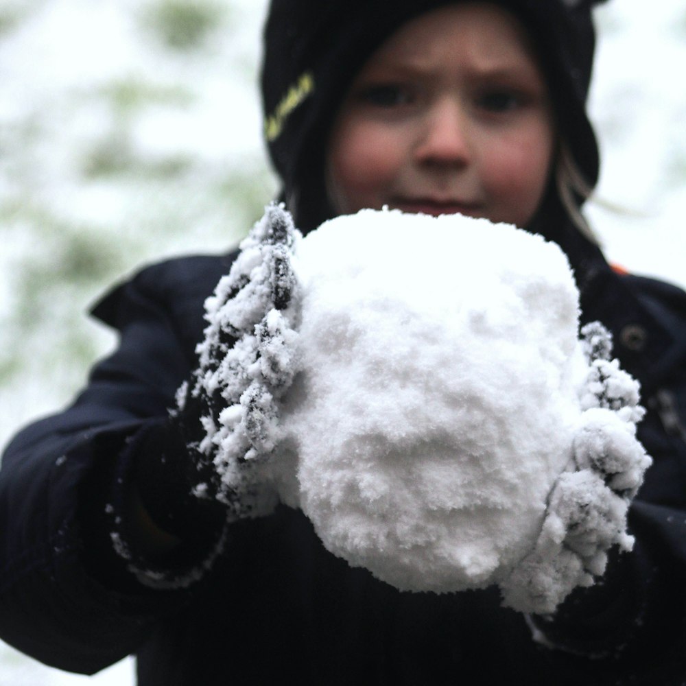 girl in black jacket holding white snow