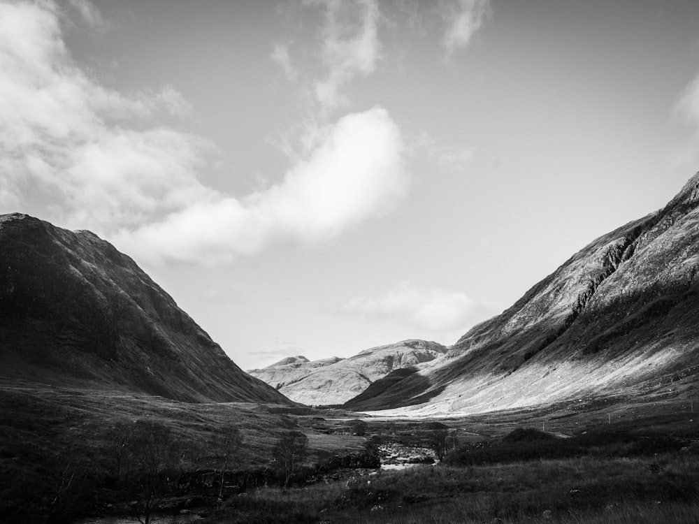 grayscale photo of mountains under cloudy sky