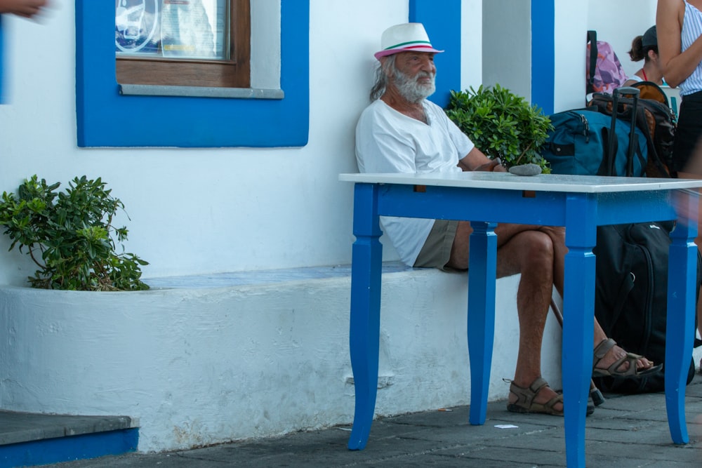 man in white button up shirt sitting on blue wooden bench