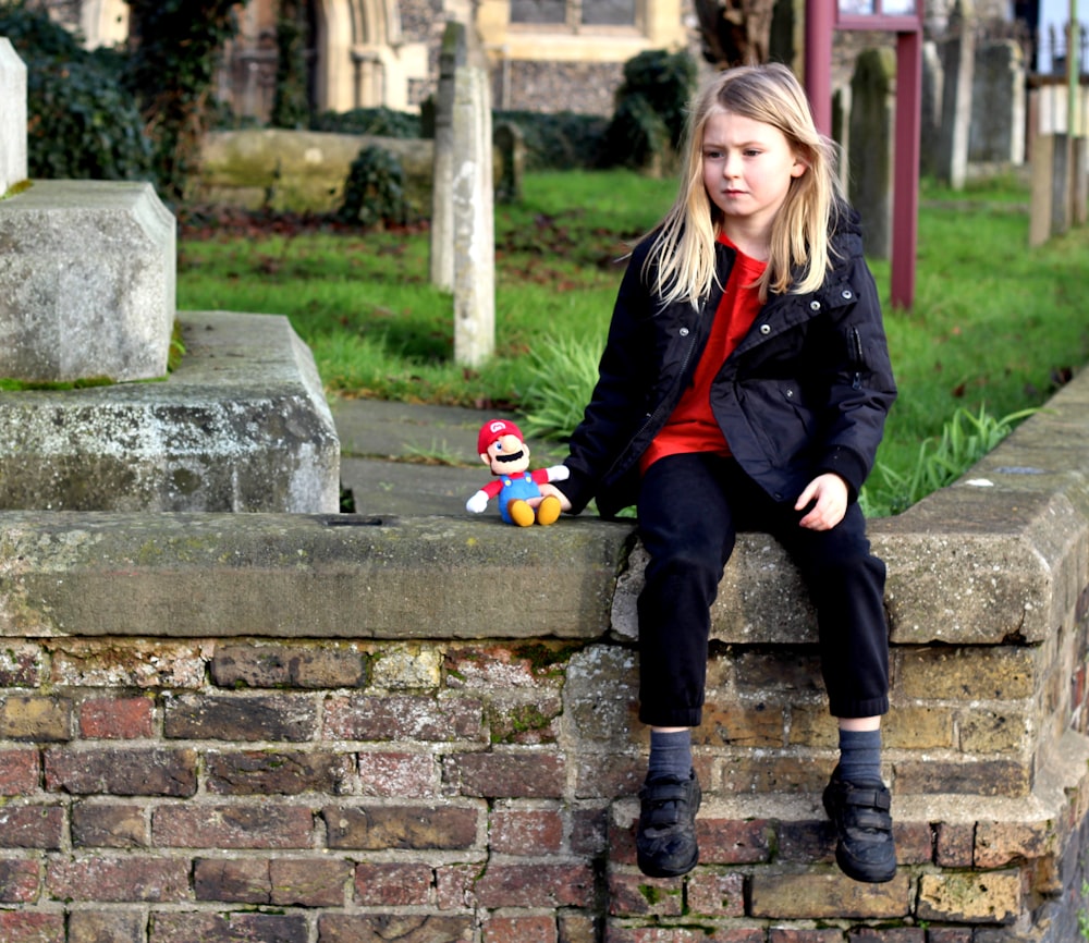 girl in black jacket sitting on concrete bench during daytime