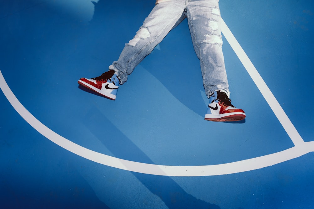 Persona in jeans denim blu e scarpe da ginnastica Nike rosse
