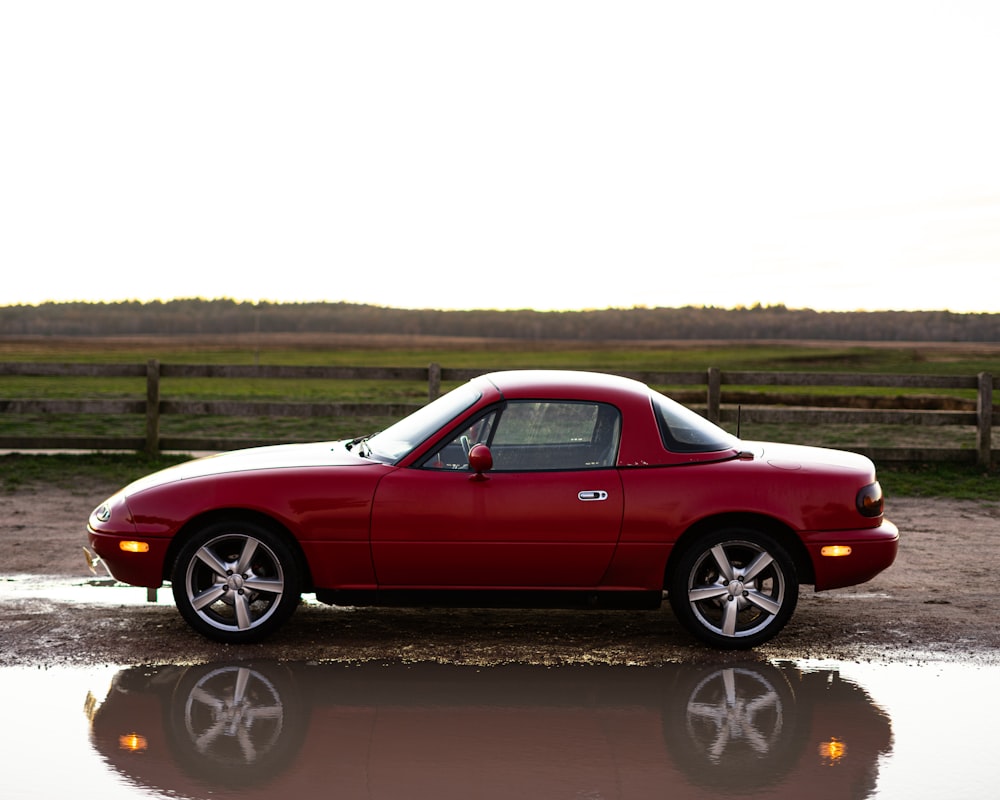 red coupe on brown dirt road during daytime