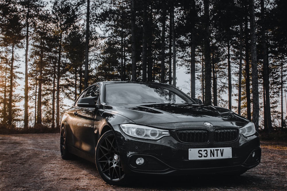 black bmw m 3 parked on dirt road near trees during daytime