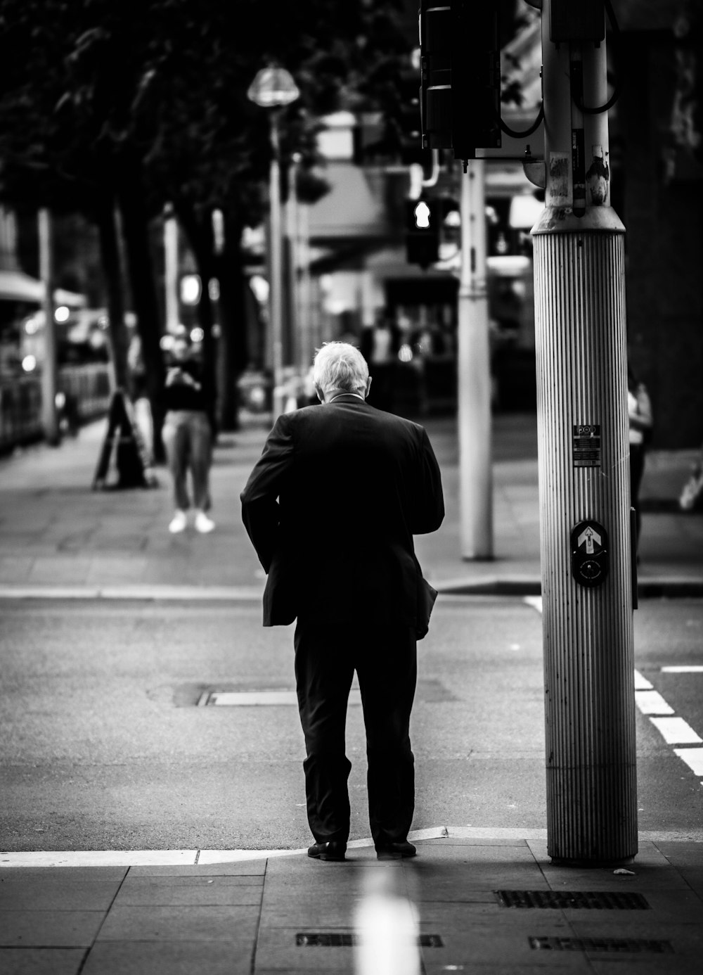 man in black suit standing on sidewalk during daytime