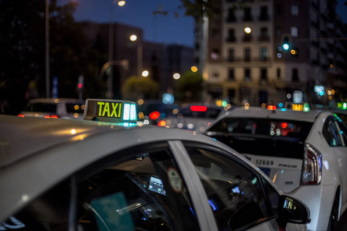 A white and black taxi cab on a road at night