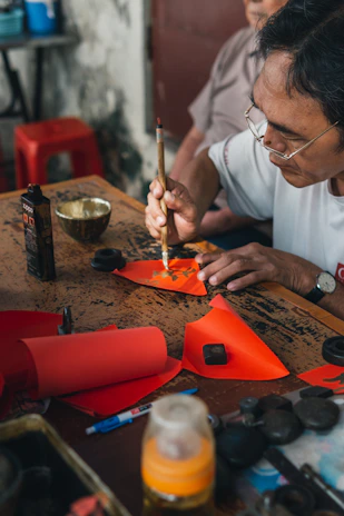 Close-up of a hand painting a traditional Taoist talisman with red cinnabar ink on textured paper