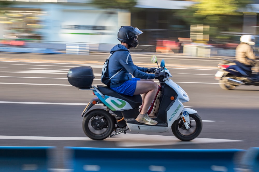 Hombre con chaqueta azul conduciendo motocicleta azul y negra