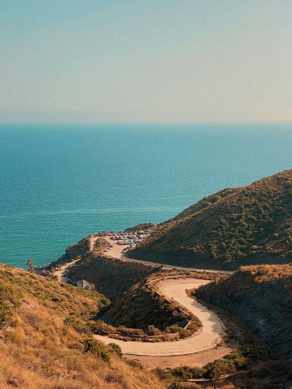 Montaña verde y marrón junto al mar azul durante el día