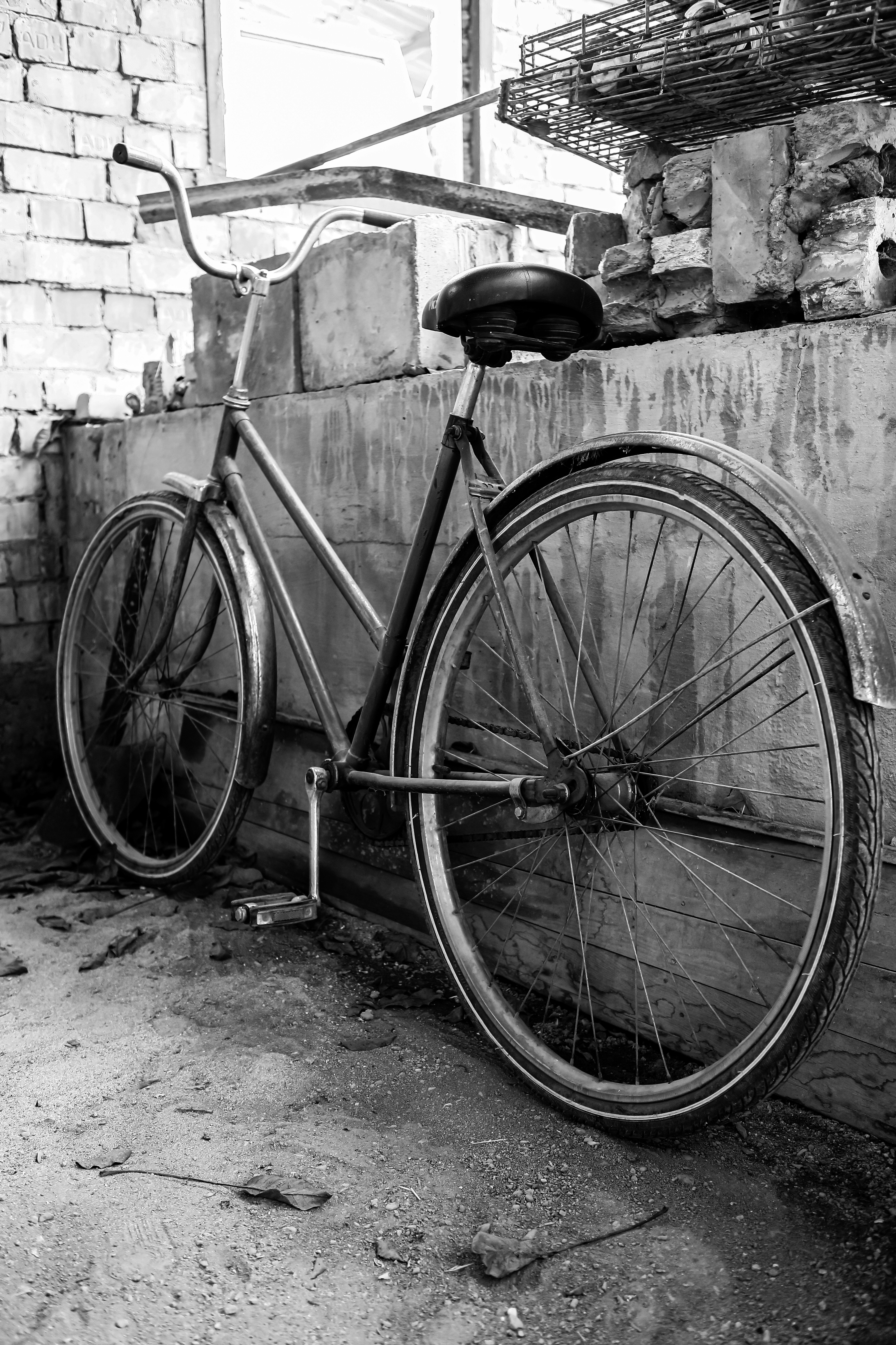 grayscale photo of city bicycle leaning on wall