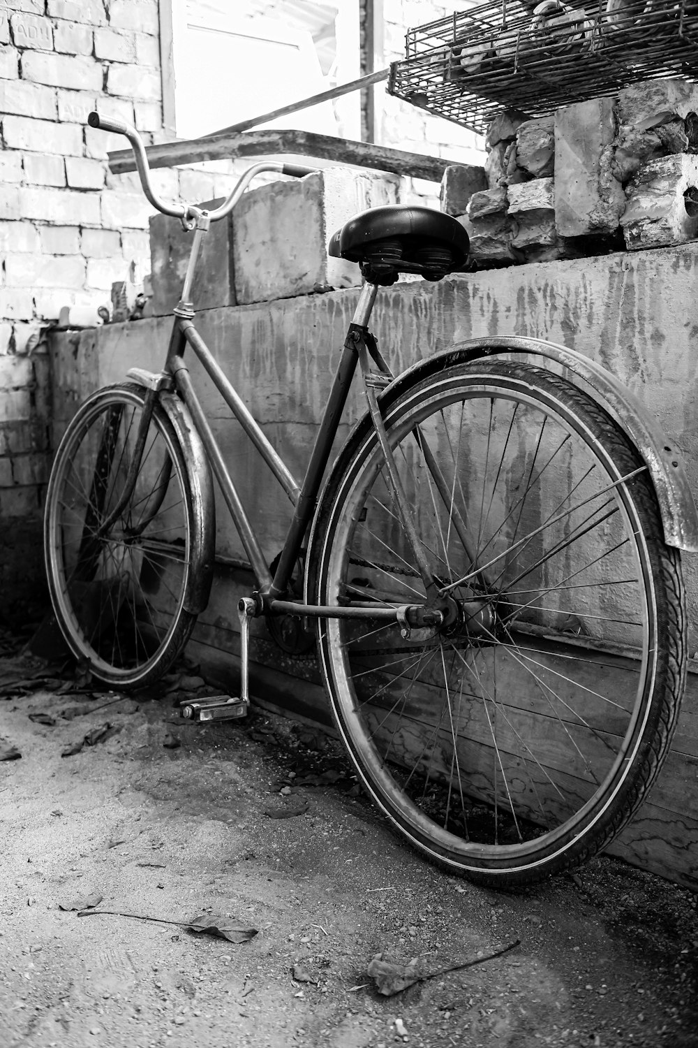 grayscale photo of city bicycle leaning on wall