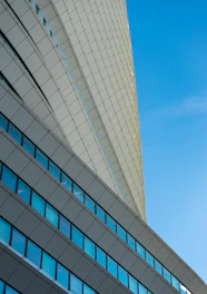 Modern corporate building with sleek solar panels seamlessly integrated into its curved facade under a clear sky.