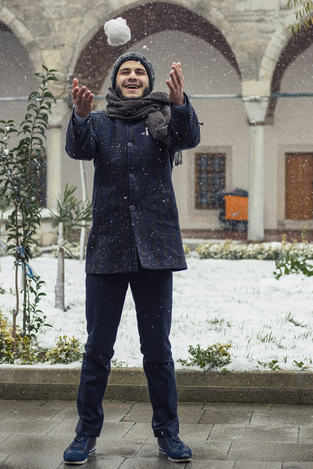 Uomo in cappotto nero in piedi vicino a piante verdi durante il giorno