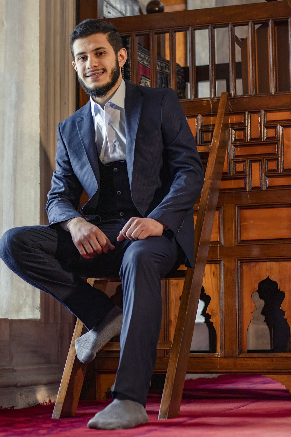 man in black suit sitting on brown wooden chair