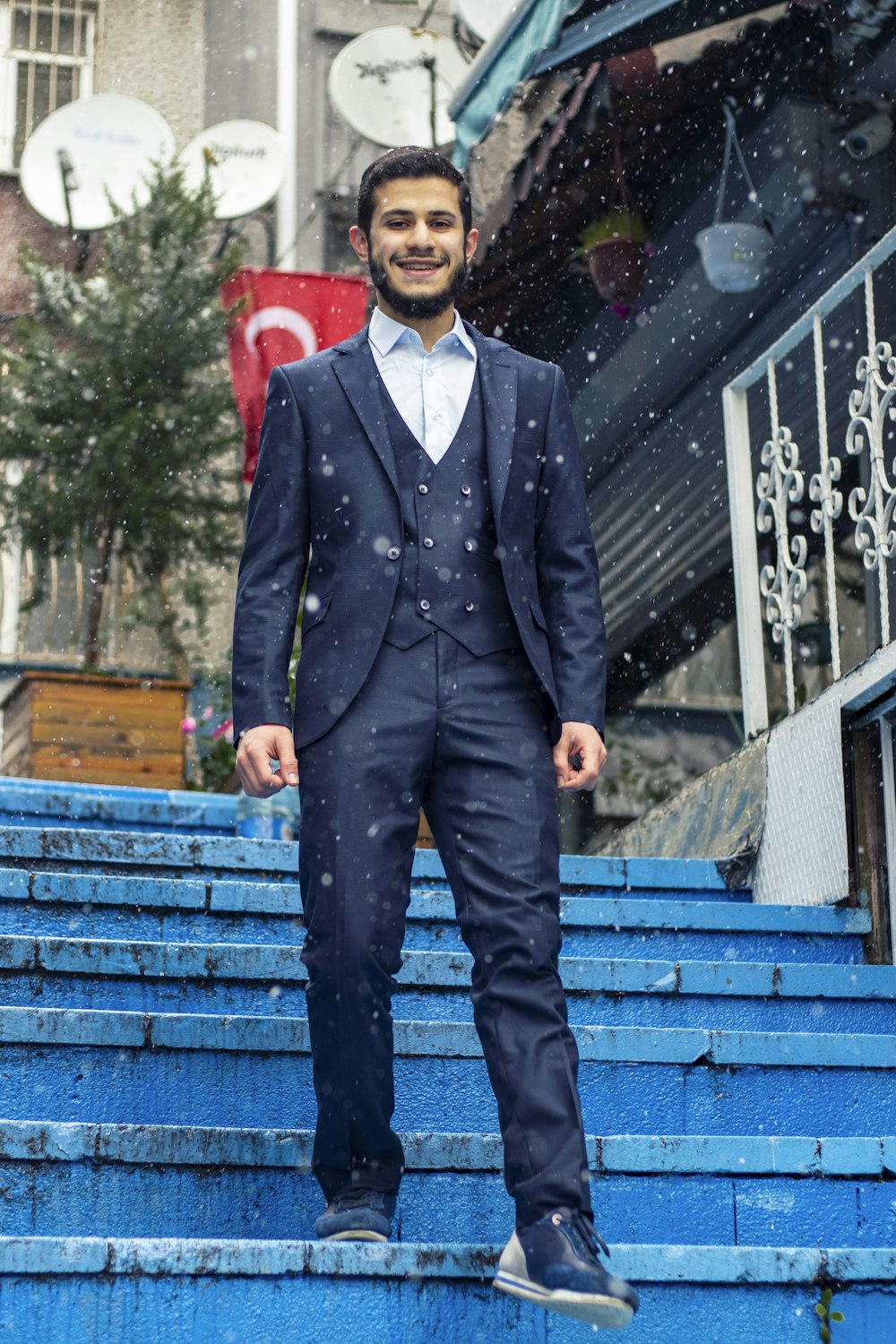 man in black suit standing on blue wooden bench