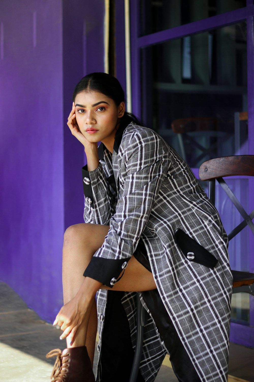 woman in black and white plaid dress shirt sitting on brown wooden chair